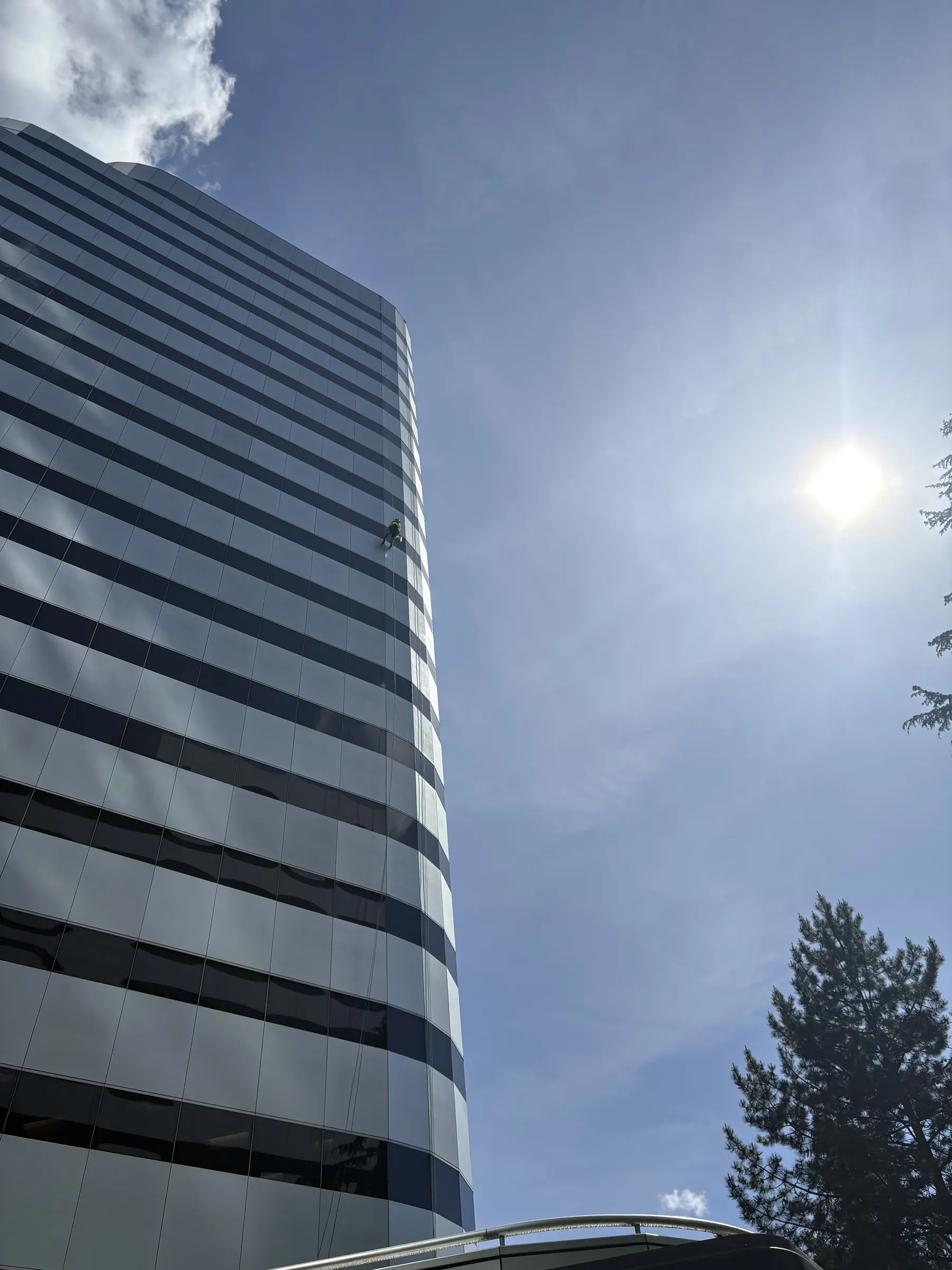 Rope access technician on the curved glass facade of an office tower